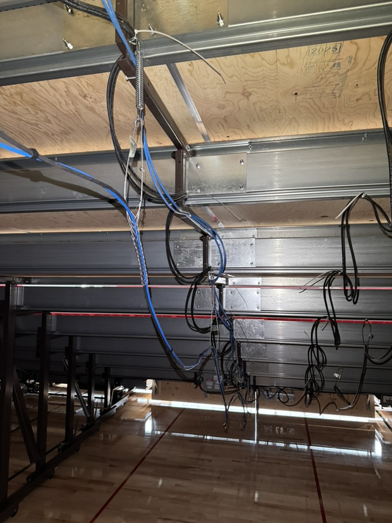 Cable routing and infrastructure work beneath the bleachers at Burlingame High School