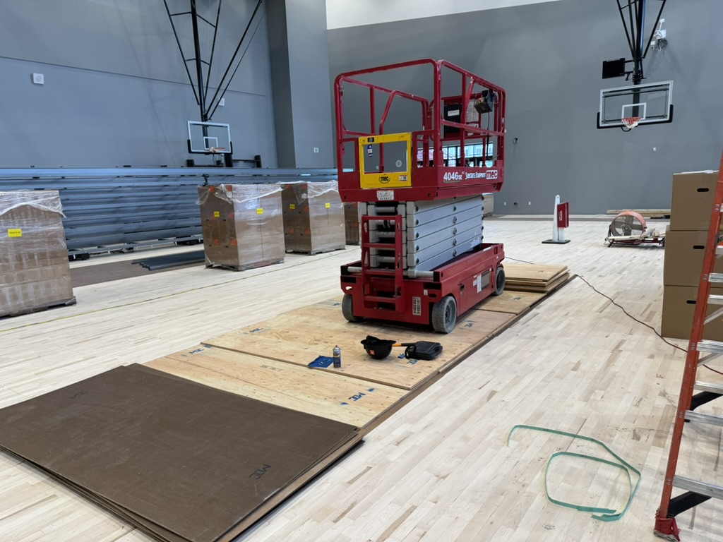 Lift staged on protective plywood over the finished gym floor at Burlingame High School